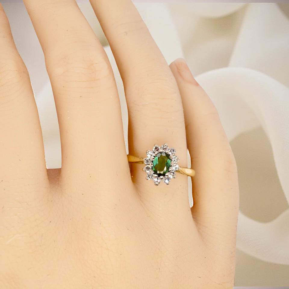 hand An elegant 18 carat gold cluster ring featuring a beautifully proportioned 6 × 4mm green tourmaline