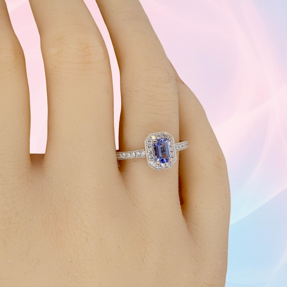 hand An elegant cluster ring that features to the centre a rectangular tanzanite gemstone that measures 6x4mm (est 0.50 carats) AAA colour.
