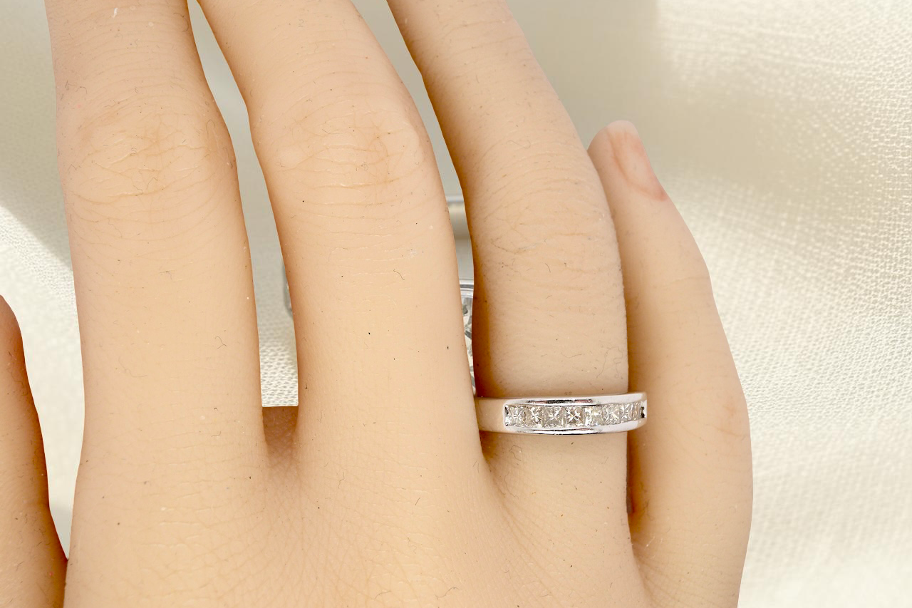 hand An elegant half-hoop eternity ring set with nine princess-cut white diamonds, each measuring approximately 2.5mm, with a total estimated diamond weight of 0.90 carats.
