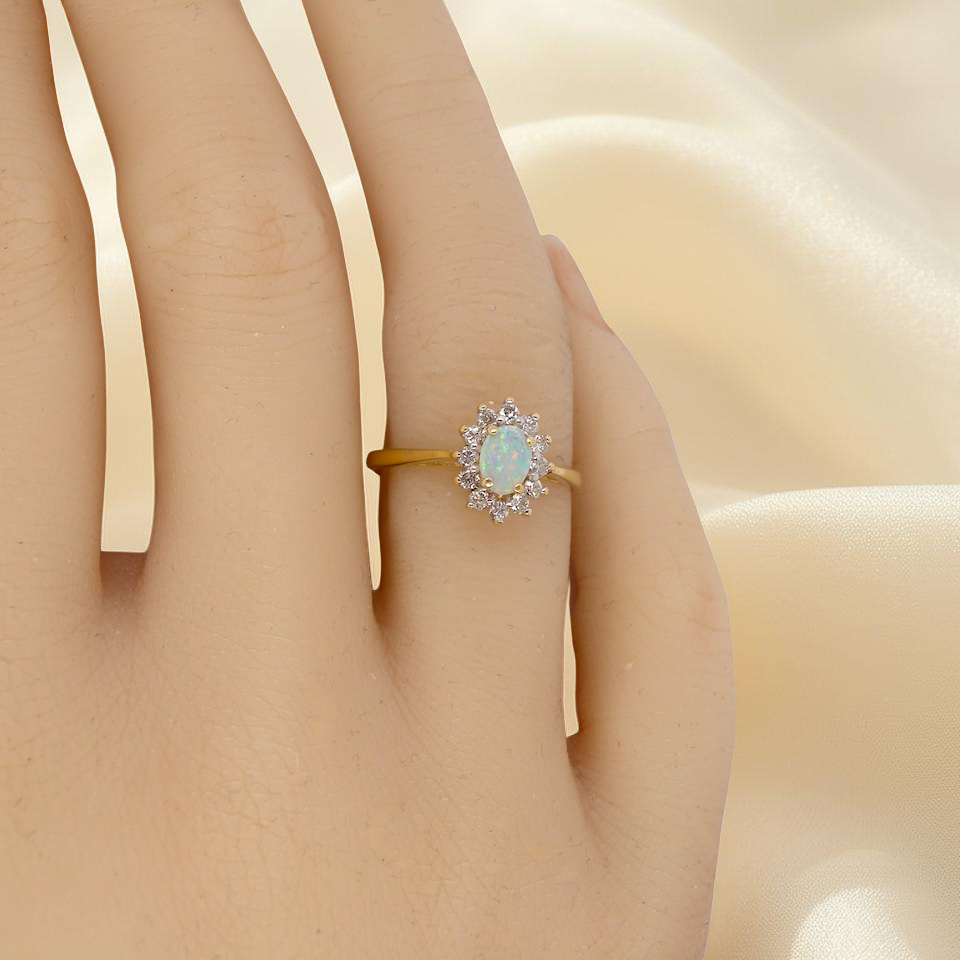 hand An elegant cluster ring featuring a white opal centre stone measuring 6 × 4mm, displaying a lively and attractive play of colour.