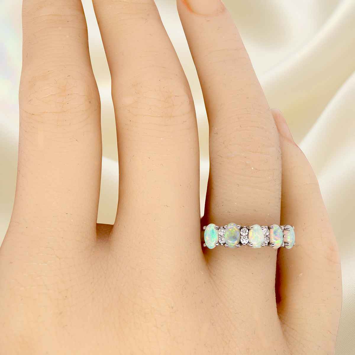 hand An elegant opal and diamond half hoop ring, featuring five oval opals with lively play of colour. Each opal measures 5 x 3mm, with an estimated total opal weight of approximately 0.75 carats, all claw set to maximise light and colour.