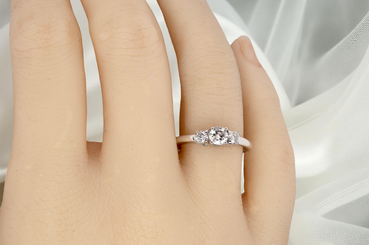 hand An elegant trilogy ring set with three brilliant-cut white diamonds,