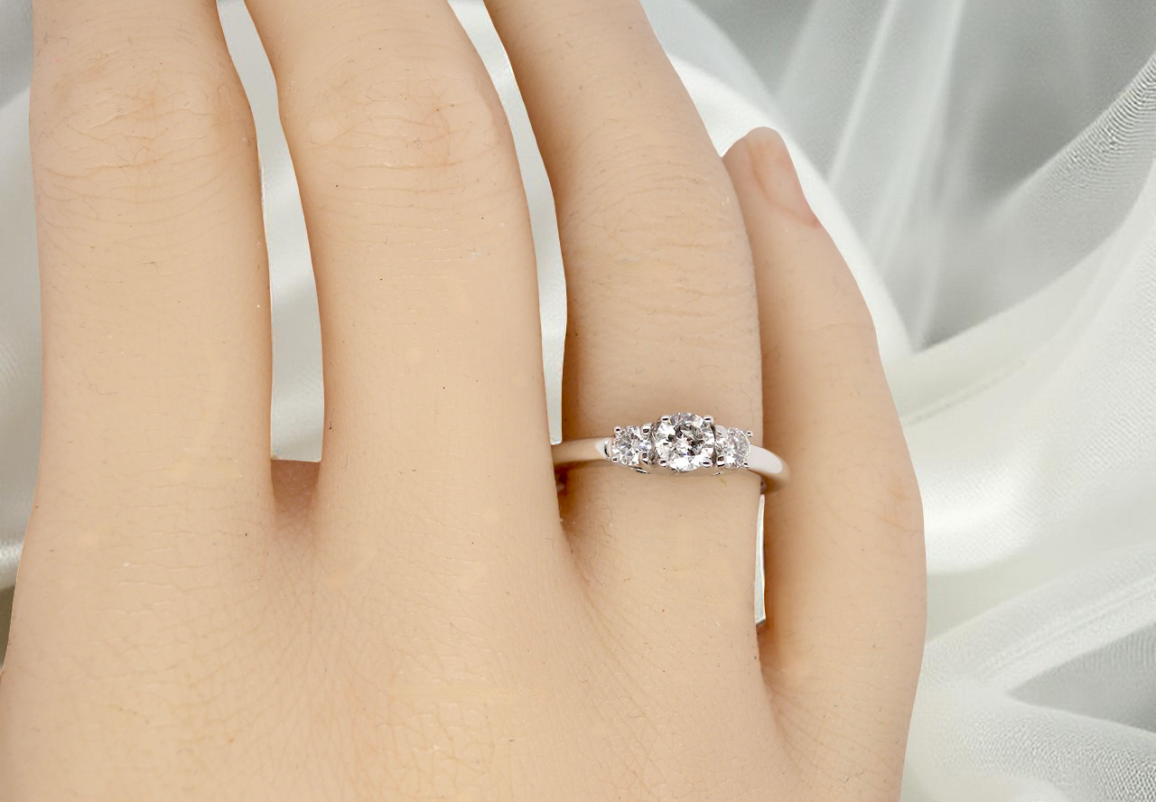 hand An elegant trilogy ring set with three brilliant-cut white diamonds,