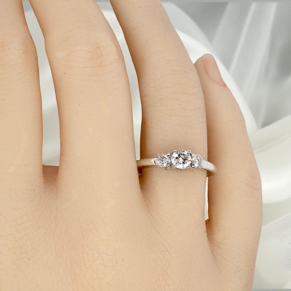 hand An elegant trilogy ring set with three brilliant-cut white diamonds,