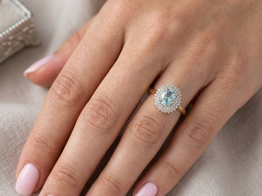 hand An impressive cluster ring that features to the centre an oval cut blue topaz gemstone, 8x6mm sky blue colour.
Complimented by an outer double halo of diamonds