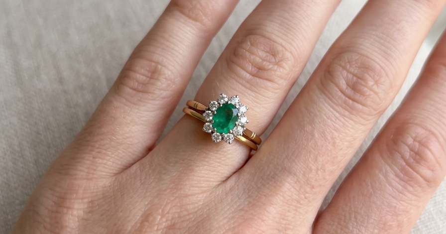 hand Features an oval cut emerald centre stone, vibrant green hues, measures 9x6mm(est 1.75 carats) . Complimented by an outer halo of ten 2.7mm brilliant cut white diamonds (est total 0.60 carats) colour i-j, clarity S.
