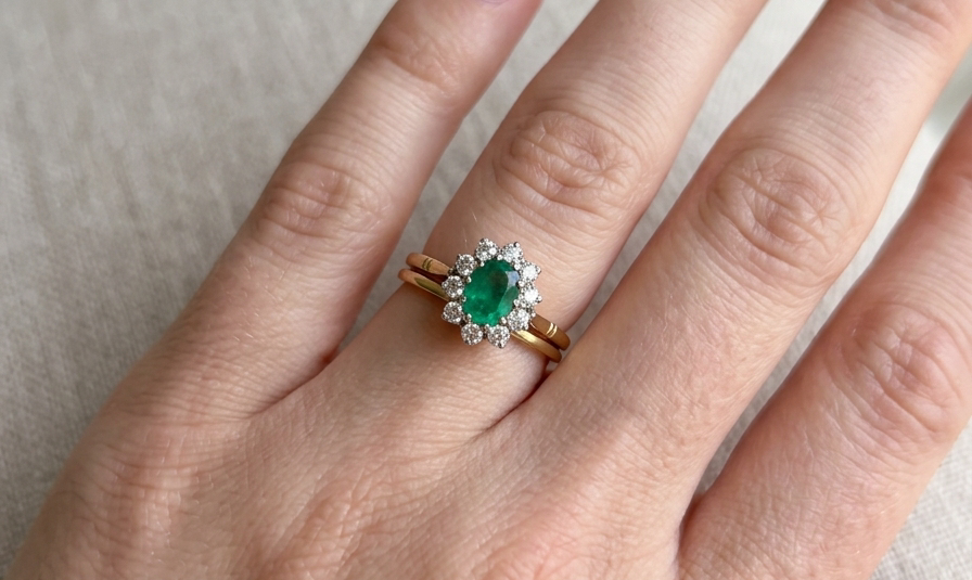 hand Features an oval cut emerald centre stone, vibrant green hues, measures 9x6mm(est 1.75 carats) . Complimented by an outer halo of ten 2.7mm brilliant cut white diamonds (est total 0.60 carats) colour i-j, clarity S.