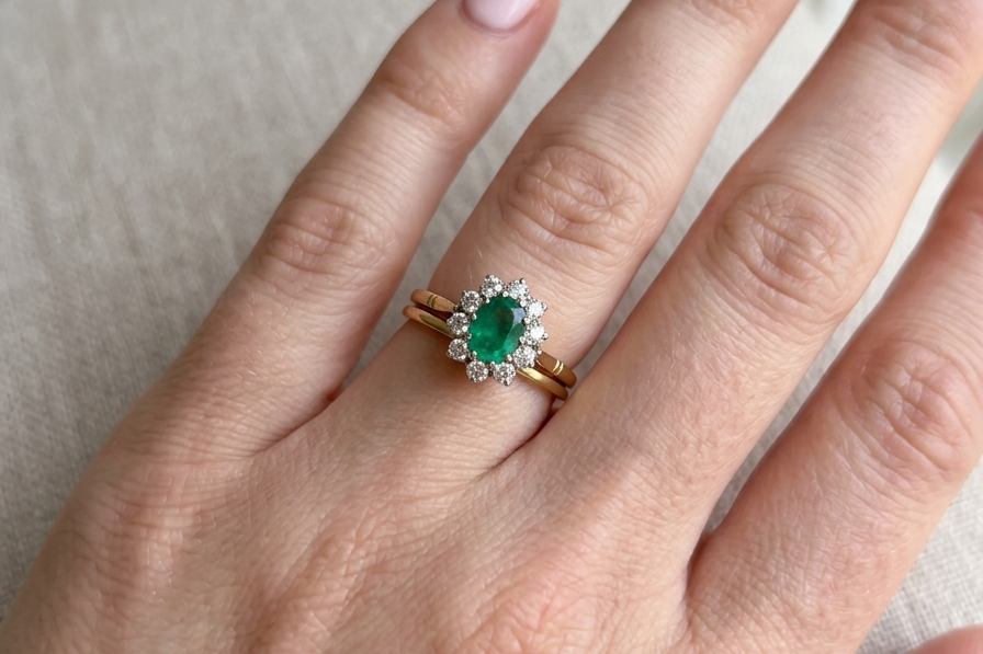 hand Features an oval cut emerald centre stone, vibrant green hues, measures 9x6mm(est 1.75 carats) . Complimented by an outer halo of ten 2.7mm brilliant cut white diamonds (est total 0.60 carats) colour i-j, clarity S.