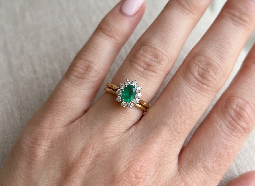 hand Features an oval cut emerald centre stone, vibrant green hues, measures 9x6mm(est 1.75 carats) . Complimented by an outer halo of ten 2.7mm brilliant cut white diamonds (est total 0.60 carats) colour i-j, clarity S.