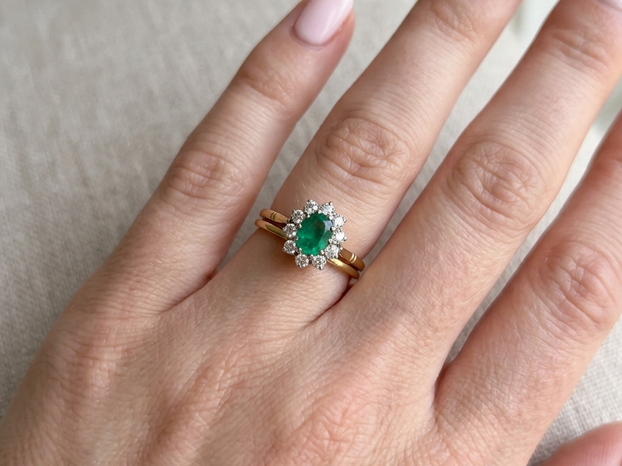 hand Features an oval cut emerald centre stone, vibrant green hues, measures 9x6mm(est 1.75 carats) . Complimented by an outer halo of ten 2.7mm brilliant cut white diamonds (est total 0.60 carats) colour i-j, clarity S.