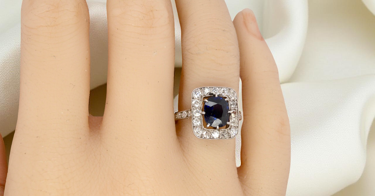 hand beautiful original Art Deco cluster ring featuring a rich, dark blue oval-cut sapphire