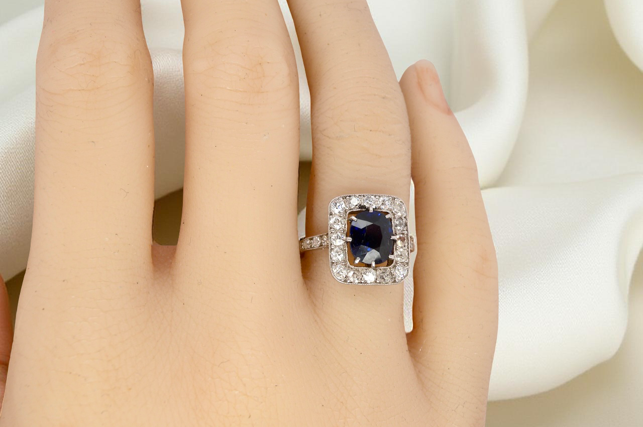 hand beautiful original Art Deco cluster ring featuring a rich, dark blue oval-cut sapphire