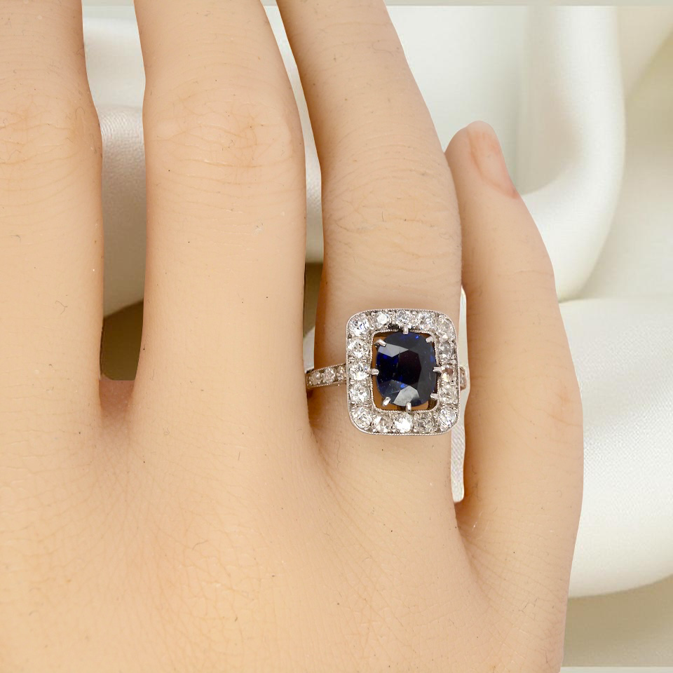 hand beautiful original Art Deco cluster ring featuring a rich, dark blue oval-cut sapphire