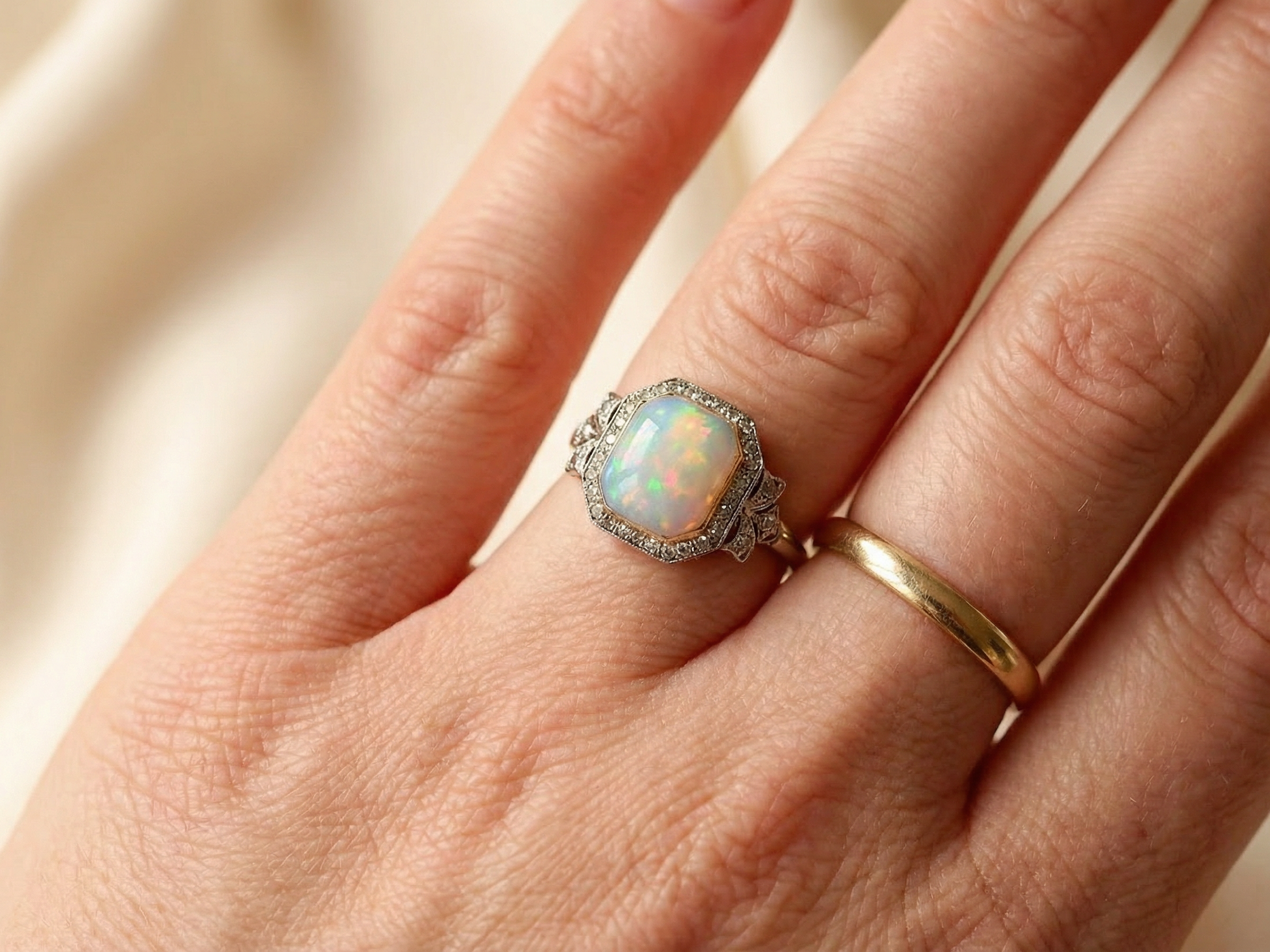 hand cabouchon cut opal shown is cushion shaped, measures 15x13 (5.78 carats) displaying a mass of vibrant colours, from flashes of fireglow orange, luminous greens, and lavender purples.
