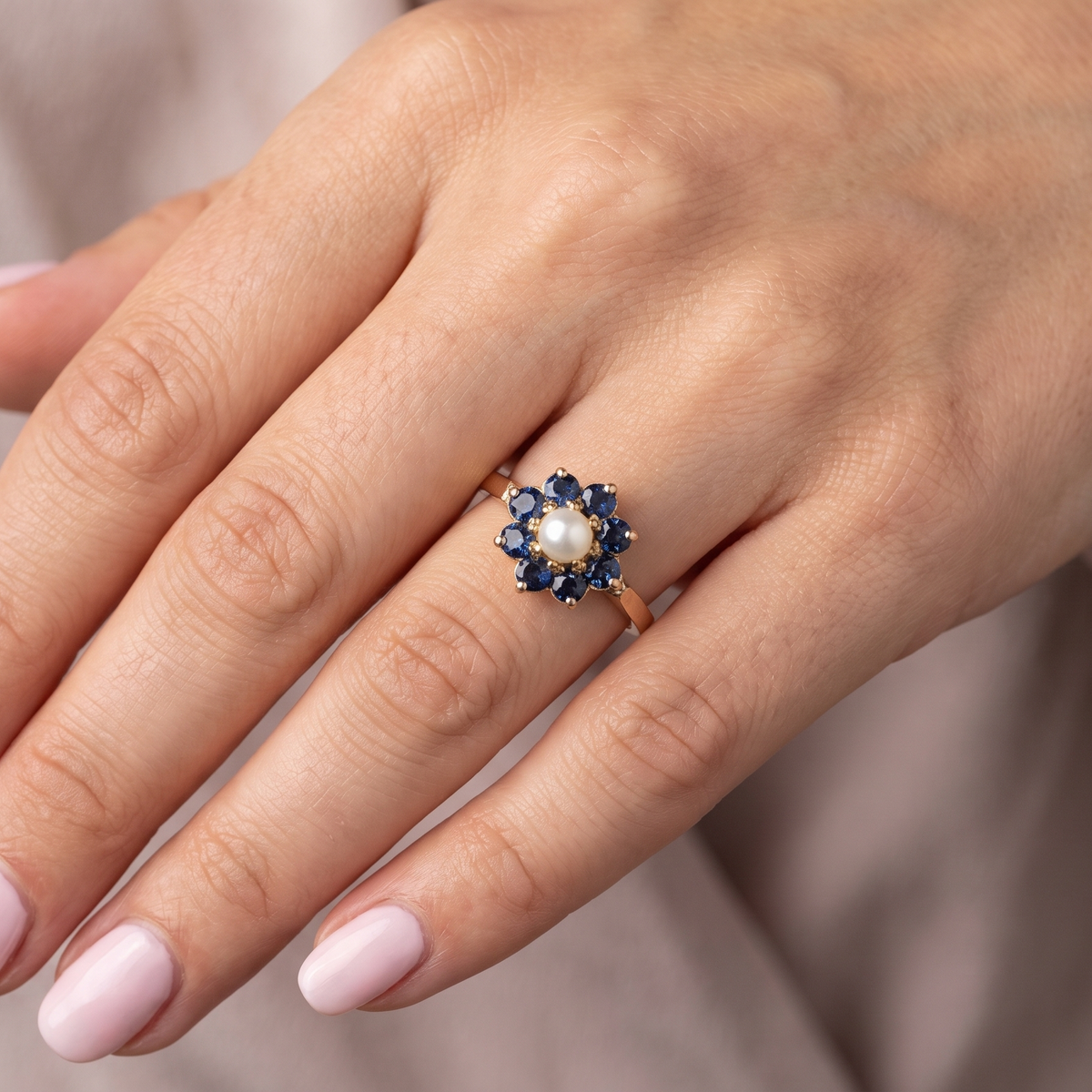 hand cluster ring, features to the centre a cultured pearl 3.6mm.
Surrounded by eight round sapphires