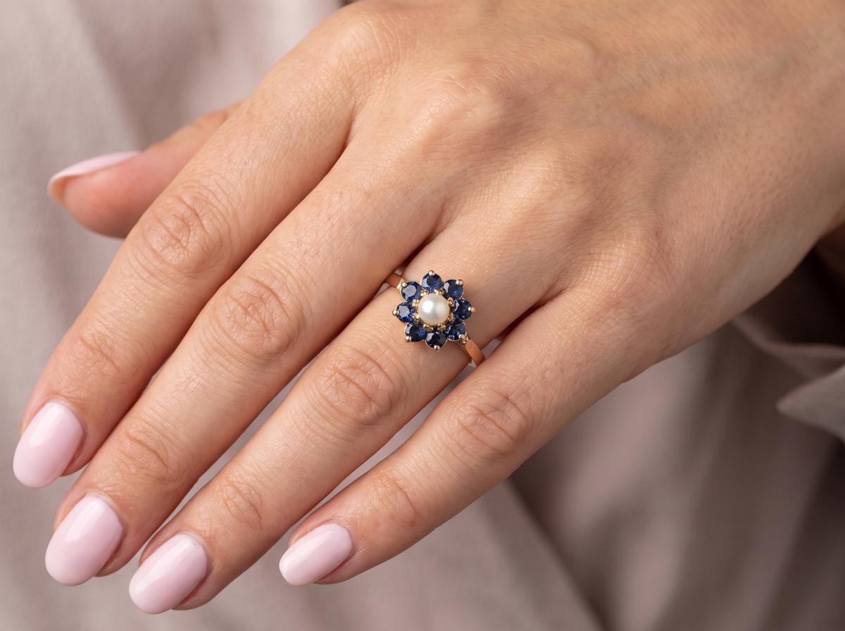 hand cluster ring, features to the centre a cultured pearl 3.6mm.
Surrounded by eight round sapphires