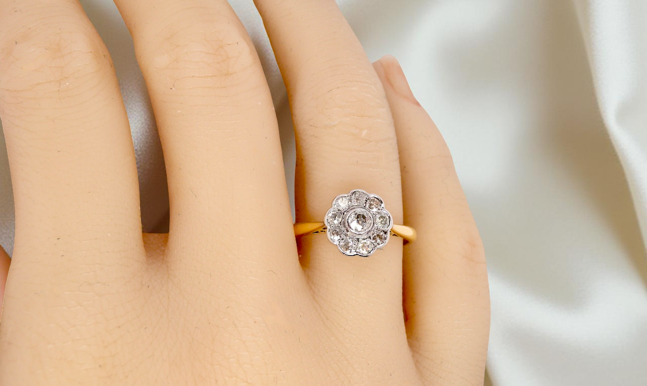 hand early 20th-century vintage diamond cluster ring, featuring a classic daisy-shaped head set with nine old brilliant-cut white diamonds.