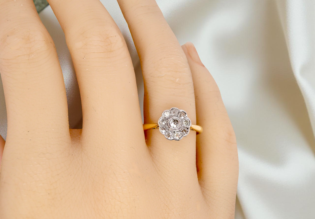 hand early 20th-century vintage diamond cluster ring, featuring a classic daisy-shaped head set with nine old brilliant-cut white diamonds.
