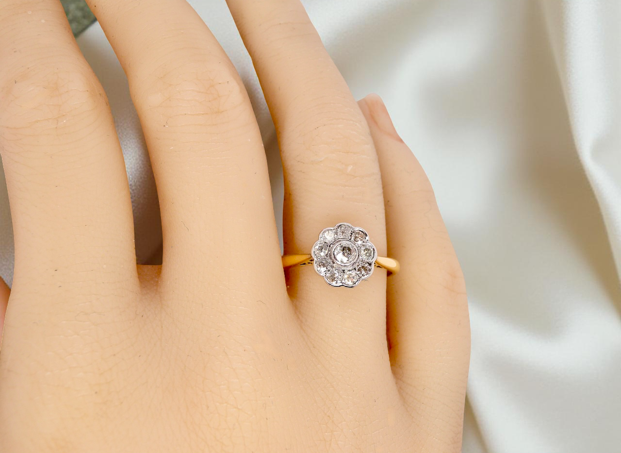 hand early 20th-century vintage diamond cluster ring, featuring a classic daisy-shaped head set with nine old brilliant-cut white diamonds.