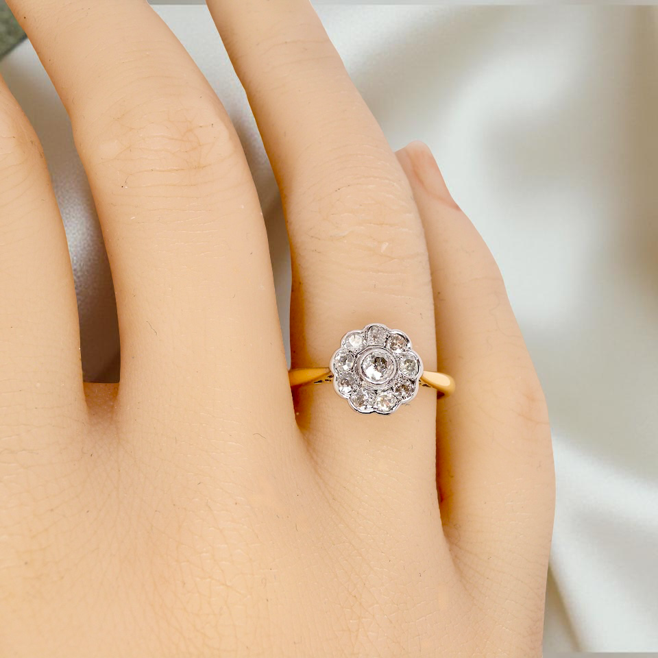 hand early 20th-century vintage diamond cluster ring, featuring a classic daisy-shaped head set with nine old brilliant-cut white diamonds.