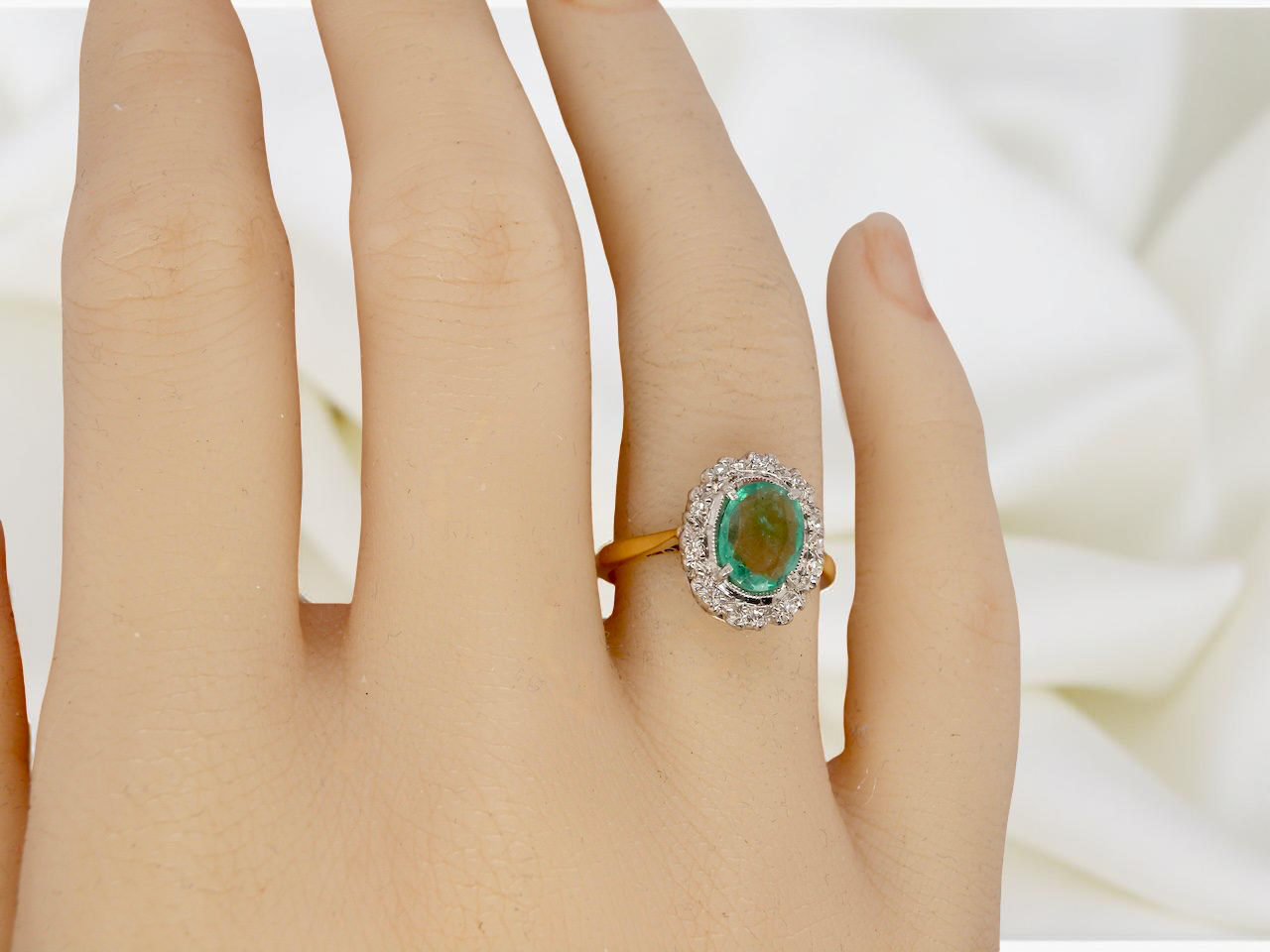 hand enchanting cluster ring that features at its centre an oval emerald,