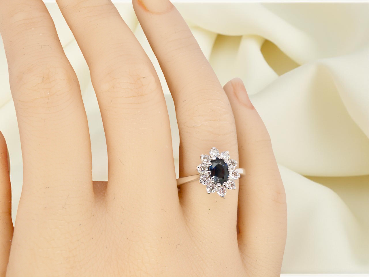 hand fine 18 carat white gold cluster ring. Features an oval cut dark blue sapphire centre stone