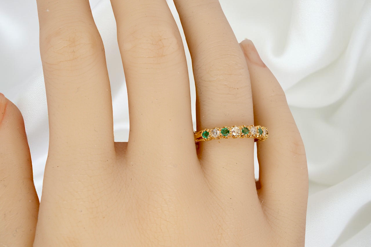 hand half-eternity ring set with alternating emeralds and diamonds.