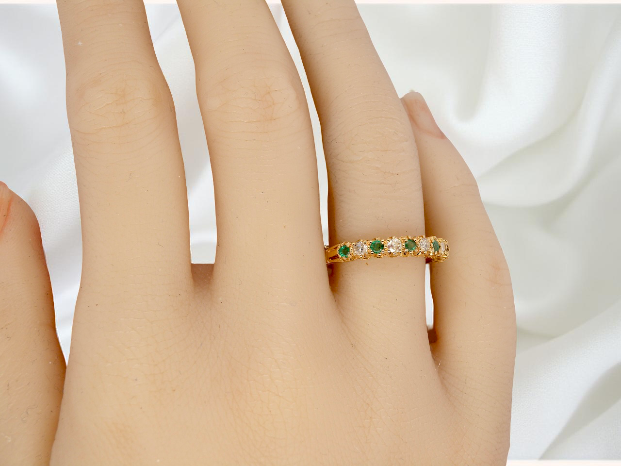 hand half-eternity ring set with alternating emeralds and diamonds.
