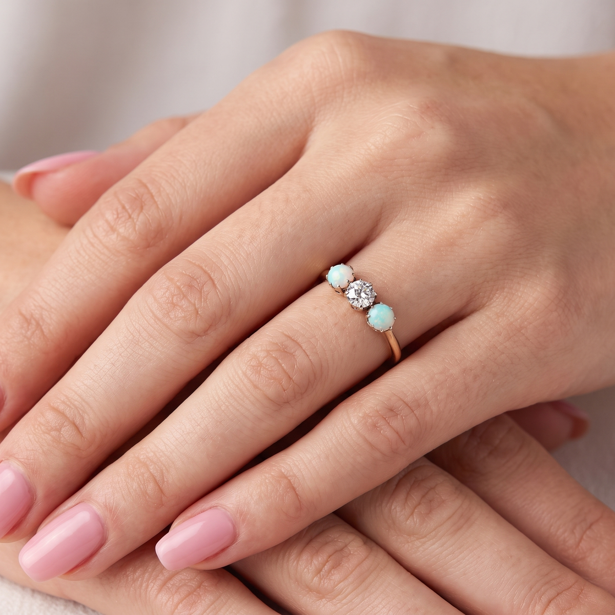hand opal A three stone ring, the centre stone an old brilliant cut white diamond 4.6mm (est 0.38 carats) colour i-j, clarity Si, claw set in platinum.
