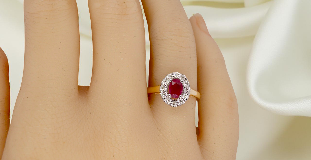 hand oval ruby measuring 6x4mm (approx. 0.44 carats) in a raspberry red hue. The centre stone is accented by a halo of twelve white diamonds