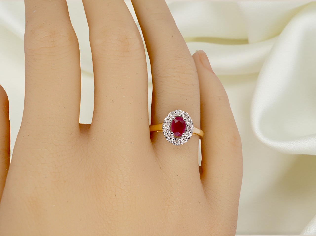 hand oval ruby measuring 6x4mm (approx. 0.44 carats) in a raspberry red hue. The centre stone is accented by a halo of twelve white diamonds