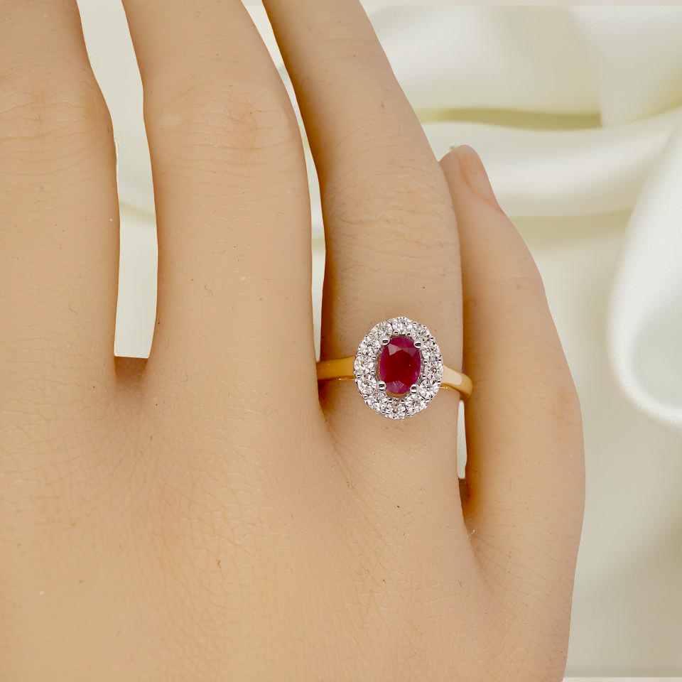 hand oval ruby measuring 6x4mm (approx. 0.44 carats) in a raspberry red hue. The centre stone is accented by a halo of twelve white diamonds