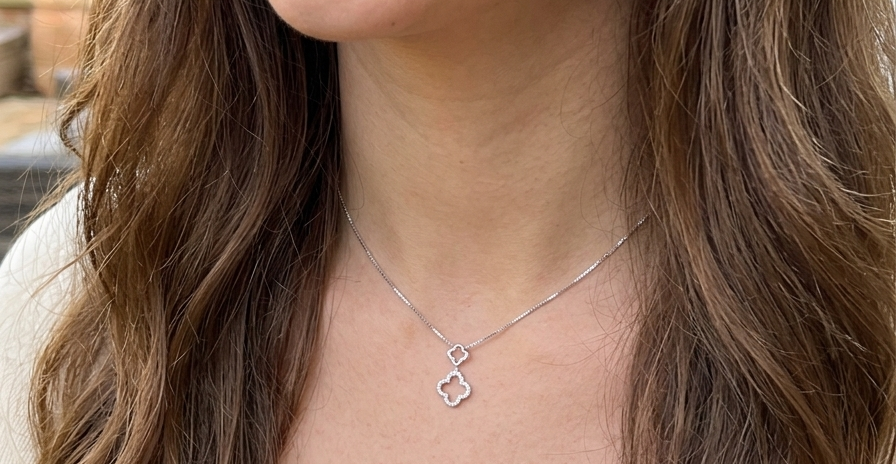 model A 9 carat white gold pendant in the 'Alhambra' style. Set with twenty four small white diamonds, carat total 0.12 carats.