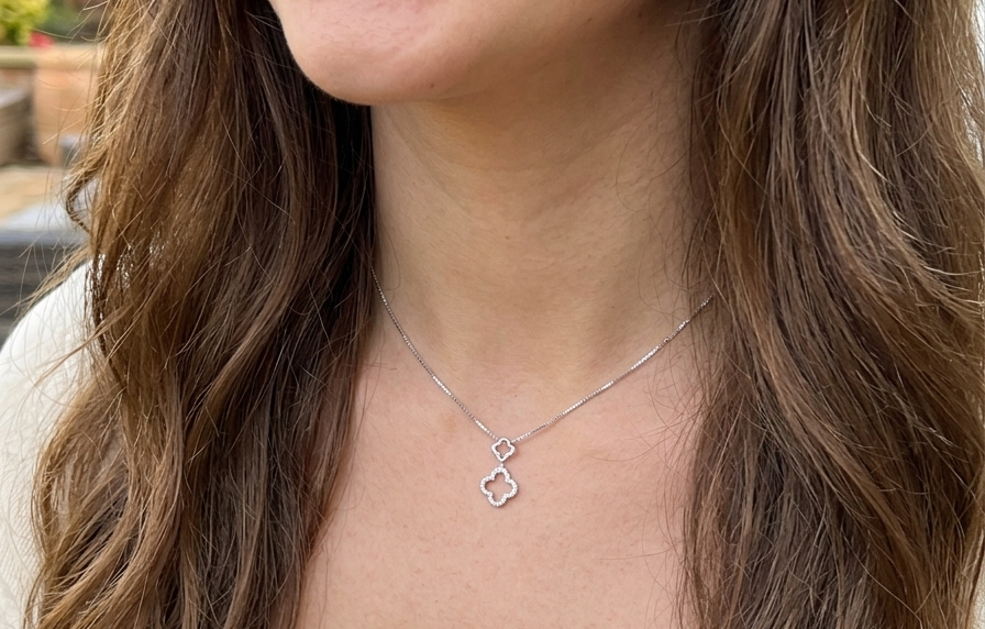 model A 9 carat white gold pendant in the 'Alhambra' style. Set with twenty four small white diamonds, carat total 0.12 carats.