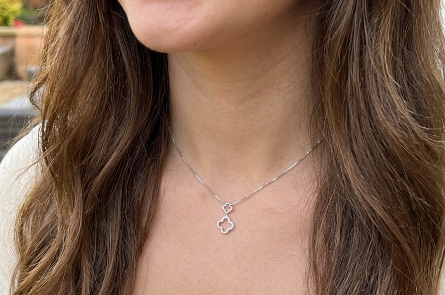 model A 9 carat white gold pendant in the 'Alhambra' style. Set with twenty four small white diamonds, carat total 0.12 carats.