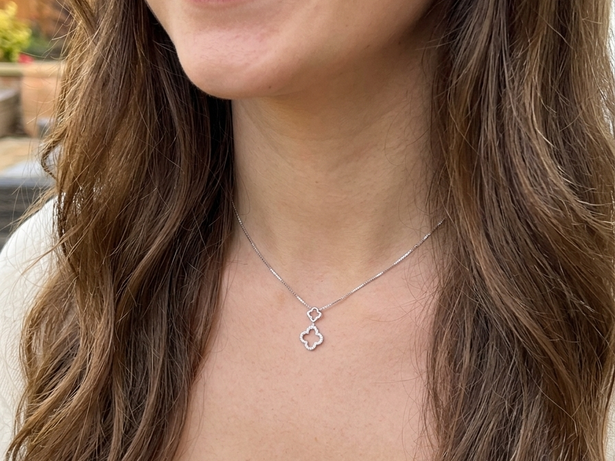 model A 9 carat white gold pendant in the 'Alhambra' style. Set with twenty four small white diamonds, carat total 0.12 carats.