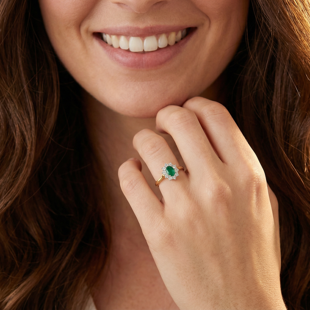 model A fine traditional emerald and diamond cluster ring, featuring a vibrant oval-cut emerald to the centre measuring approximately 7 × 5 mm