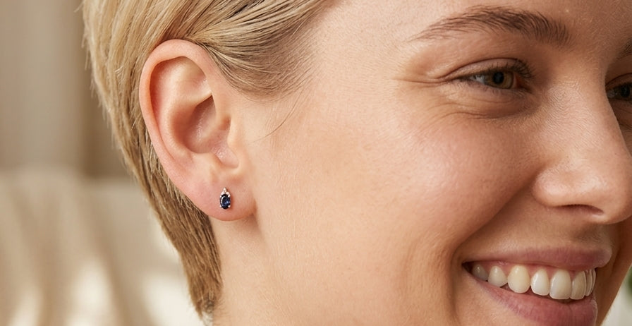model A pair of 18 carat gold earrings*. Set with a dark blue oval cut sapphire 6x4mm, claw set.
Above each, three small white diamonds, overall size 9x4.6mm, weight each 1 gram.