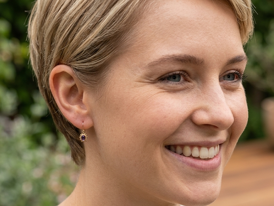 model A pair of drop earrings. Each set with a cabouchon cut amethyst 6x4mm and set with an antique look border.