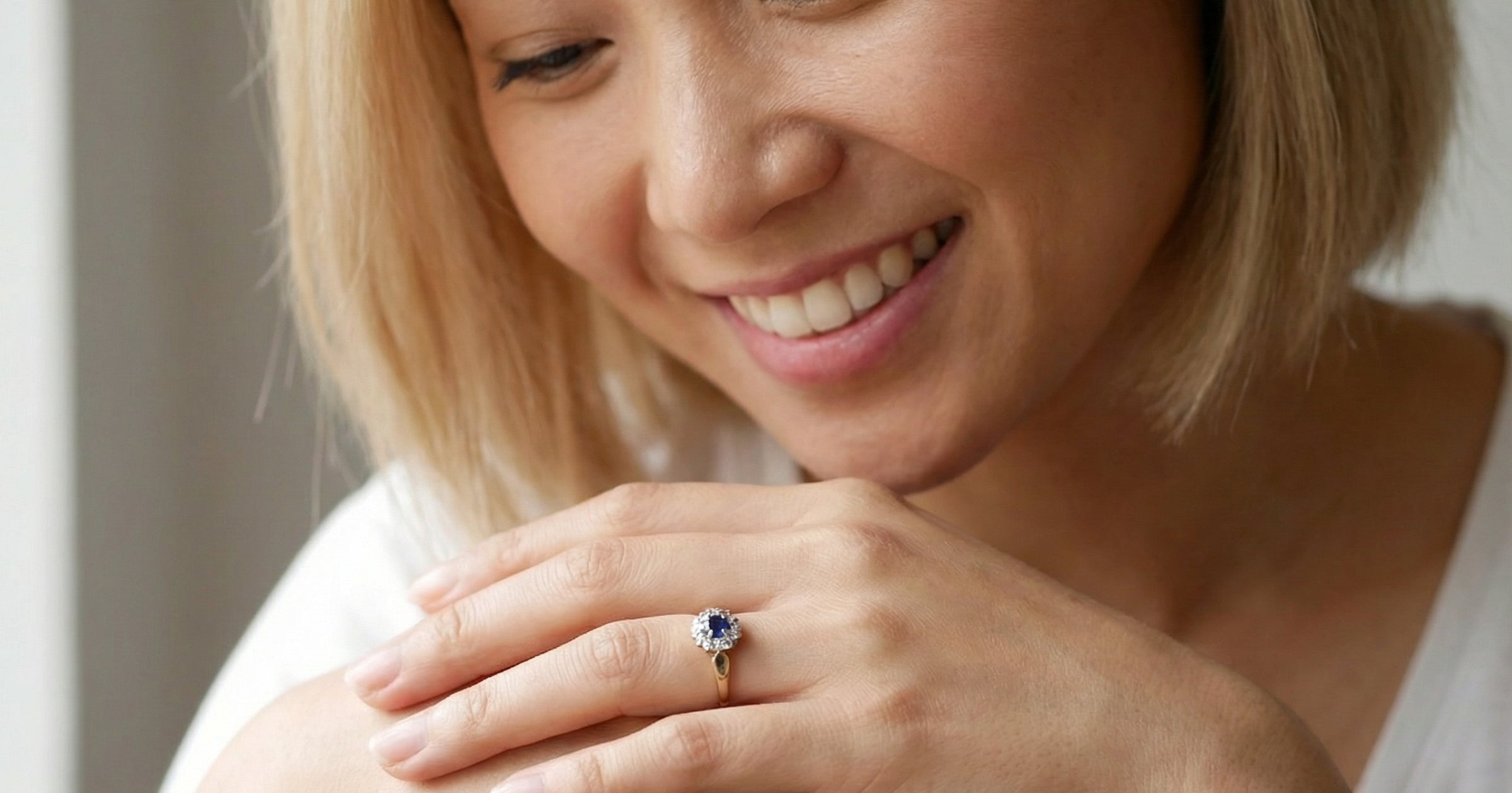 model An 18 carat gold cluster ring, features to the centre a dark blue sapphire, 3.6mm diameter. Claw set.