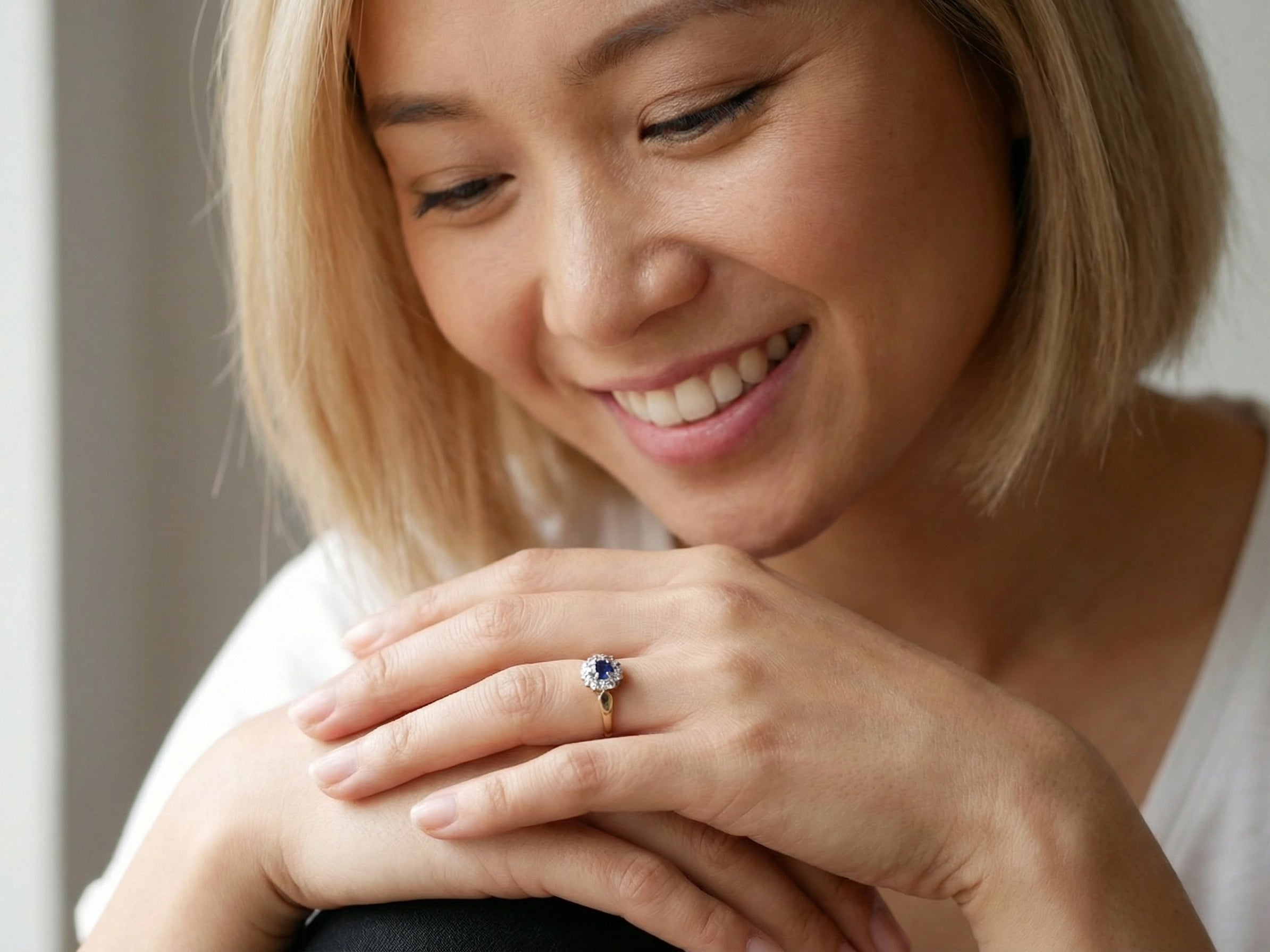 model An 18 carat gold cluster ring, features to the centre a dark blue sapphire, 3.6mm diameter. Claw set.
