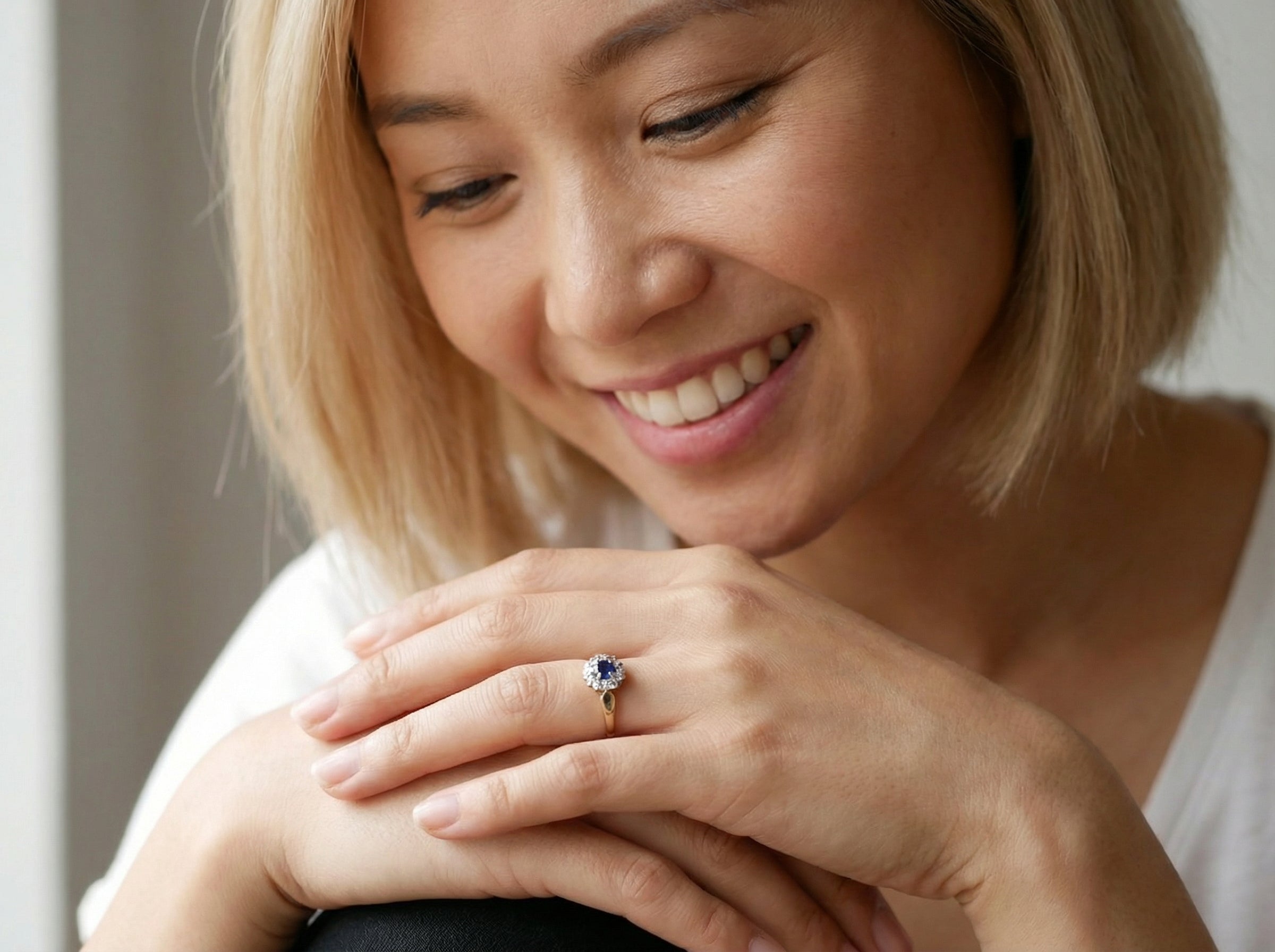 model An 18 carat gold cluster ring, features to the centre a dark blue sapphire, 3.6mm diameter. Claw set.