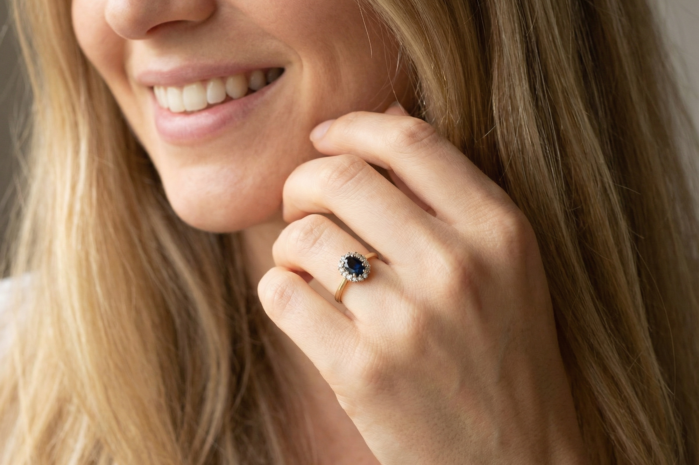 modelAn elegant 18 carat gold cluster ring featuring a striking inky dark blue sapphire at its centre.