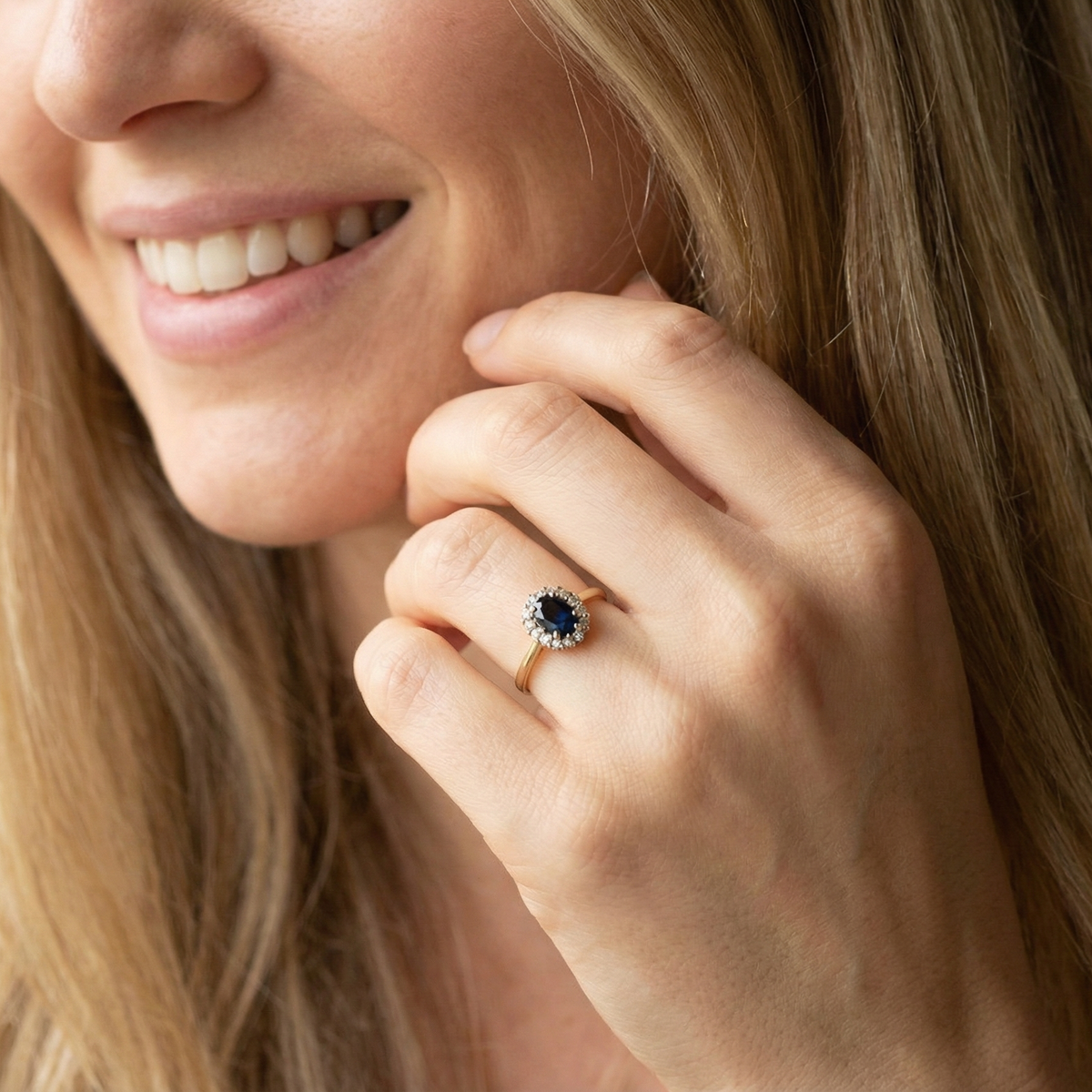 modelAn elegant 18 carat gold cluster ring featuring a striking inky dark blue sapphire at its centre.