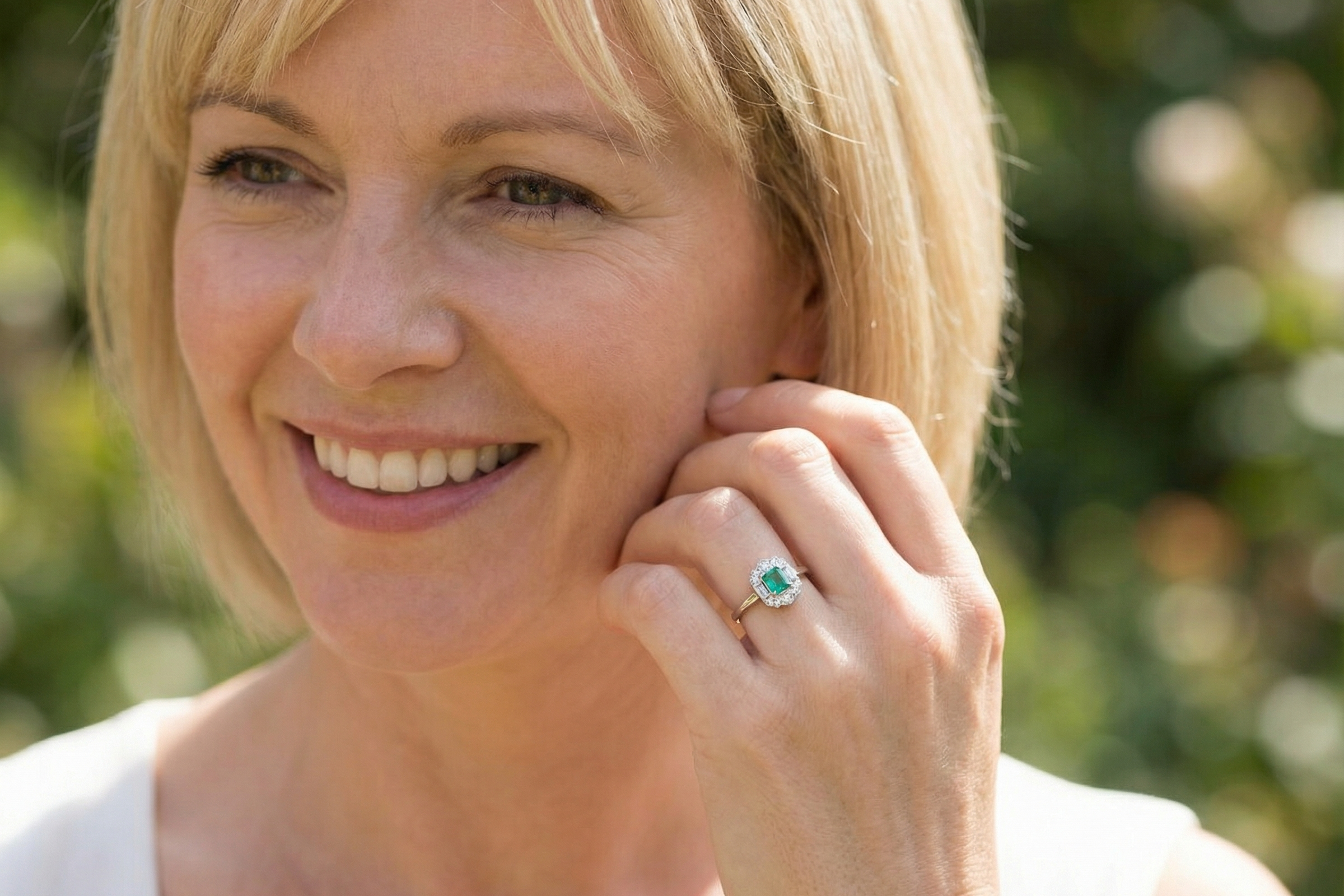 model An elegant Art Deco–style cluster ring of plaque design, centred with a square step-cut emerald measuring approximately 4.5 × 4.5 mm (estimated 0.40 carats). The emerald displays a vibrant, lively green colour and is beautifully framed by diamonds.