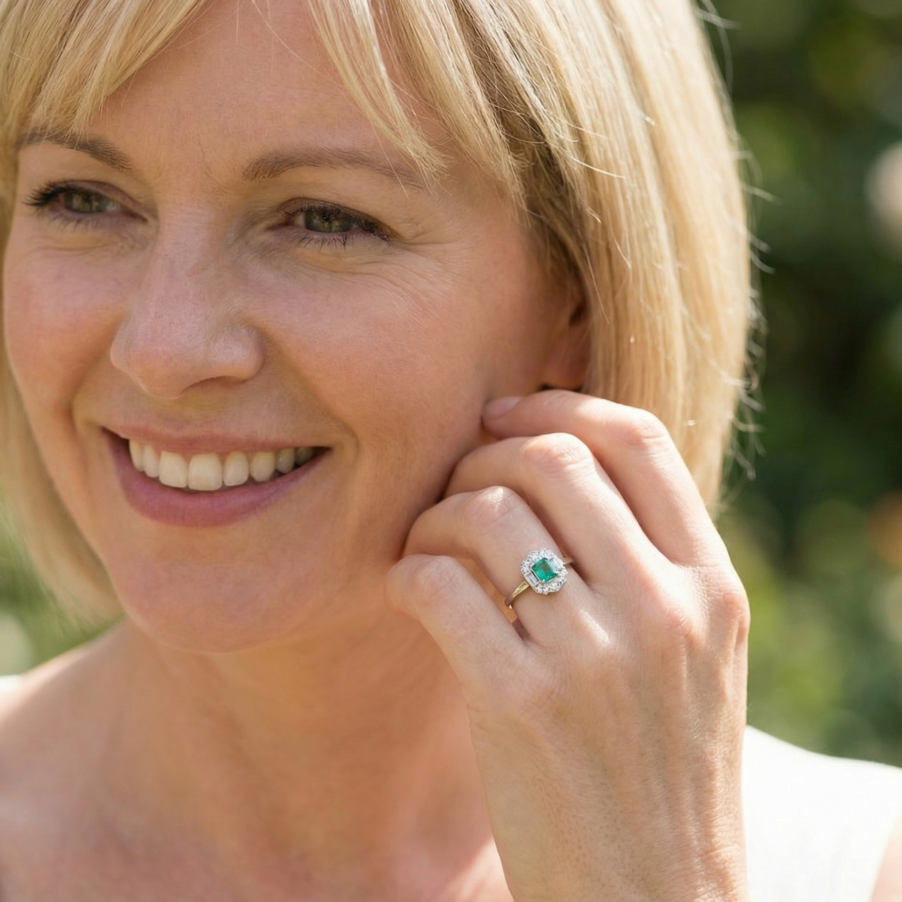 model An elegant Art Deco–style cluster ring of plaque design, centred with a square step-cut emerald measuring approximately 4.5 × 4.5 mm (estimated 0.40 carats). The emerald displays a vibrant, lively green colour and is beautifully framed by diamonds.