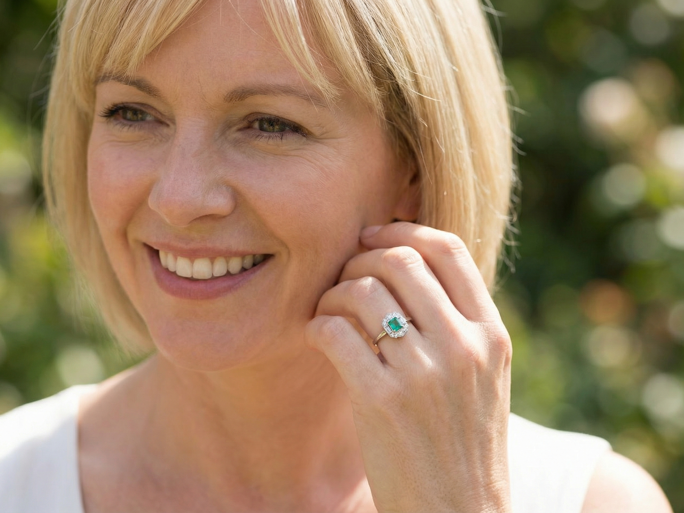 model An elegant Art Deco–style cluster ring of plaque design, centred with a square step-cut emerald measuring approximately 4.5 × 4.5 mm (estimated 0.40 carats). The emerald displays a vibrant, lively green colour and is beautifully framed by diamonds.