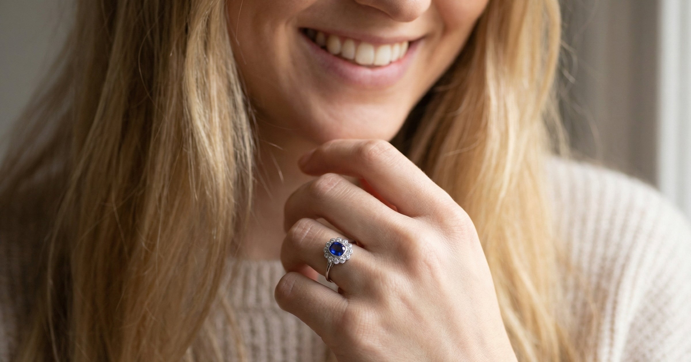 model An elegant and timeless cluster ring, centrally set with a beautiful mid to deep blue cushion-cut sapphire, measuring approximately 8 x 8mm (estimated 2.00 carats).