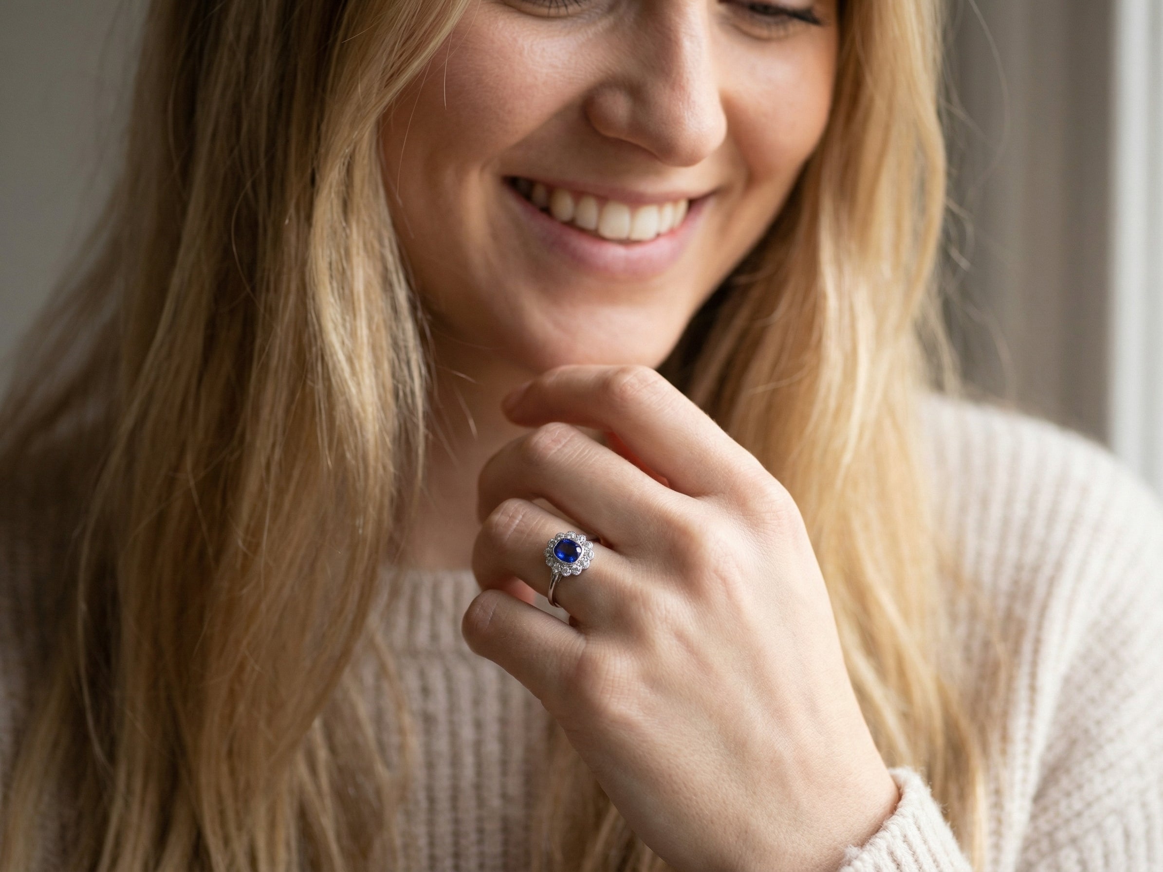 model An elegant and timeless cluster ring, centrally set with a beautiful mid to deep blue cushion-cut sapphire, measuring approximately 8 x 8mm (estimated 2.00 carats).