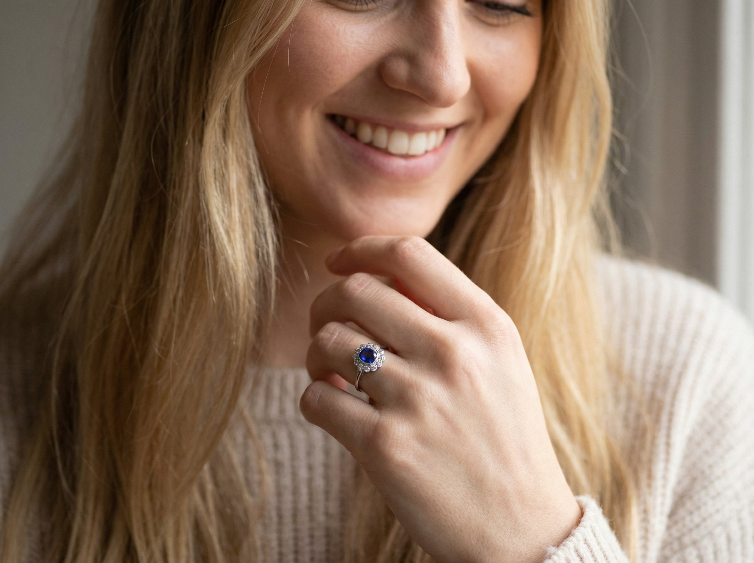 model An elegant and timeless cluster ring, centrally set with a beautiful mid to deep blue cushion-cut sapphire, measuring approximately 8 x 8mm (estimated 2.00 carats).